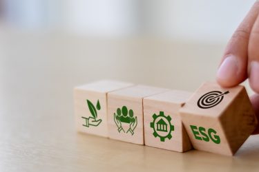 ESG concept of environmental, social and governance - hand turning over wooden blocks to show icons representing ESG